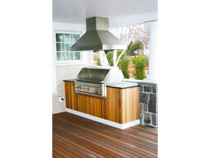 A grill on top of wooden cabinets in an outdoor kitchen.