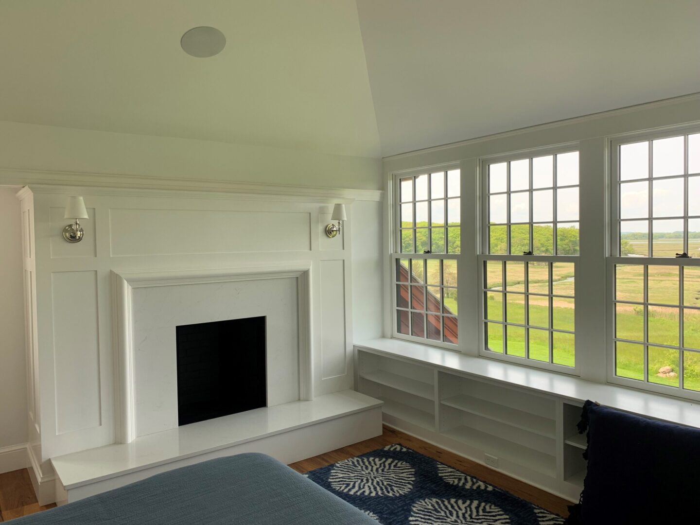 A bedroom with a fireplace and a large window.