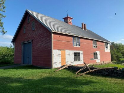 A red barn with a metal roof and a blue sky
