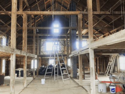 A large room with many wooden beams and a ladder.