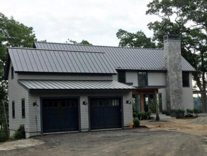 A large house with two garage doors and a metal roof.